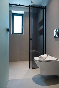 a bathroom with a toilet and a glass shower at Olive 203 in Nafplio