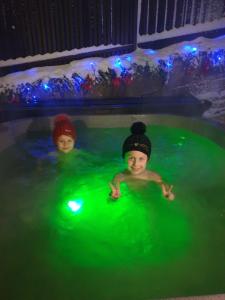 two children swimming in a pool with green lights at Mini Хаус Ясіня in Yasinya