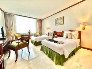 a hotel room with two beds and a piano at Hotel Sahid Jaya Solo in Solo