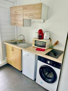 a kitchen with a washing machine and a microwave at Duplex 4 personnes Chambre vue mer Résidence O Coeur de Deshaies in Deshaies