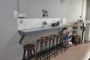 a kitchen with a counter with four bar stools at Confidence Motel in Kuah