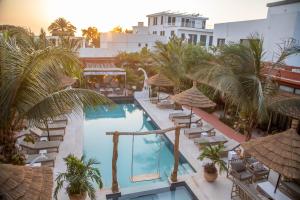 an image of a hotel pool with chairs and palm trees at Maison de clara in Ngaparou