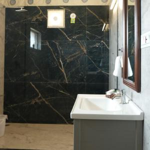 a bathroom with a sink and a black marble wall at Innara Hospitality in Mori Bera