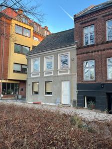 a gray house in front of two brick buildings at Charming townhouse in CityCenter Townhouse - free parking in Odense