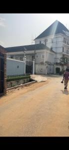 a person walking down a dirt road in front of a house at The Private Pearl Apartment in Ikeja