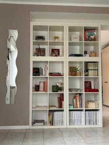 a white book shelf filled with books and a guitar at Posticino apartment in Soave