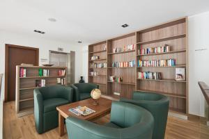 a library with green chairs and a table and bookshelves at Meliá Laguna Beach - Adults Only in Santa Maria