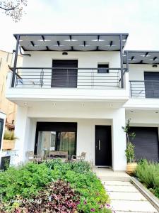 a white house with a balcony and a patio at Lygonis White Houses in Mitika
