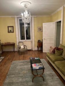 a living room with a green couch and a chandelier at LA Combe in Confolens +10 photos