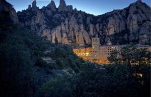 a building in front of a mountain at night at Poolside Apartment Barcelona Sant Cugat in Sant Cugat del Vallès