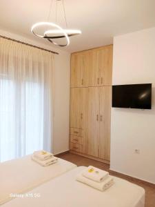 a bedroom with two white beds and a tv at Lygonis White Houses in Mitika