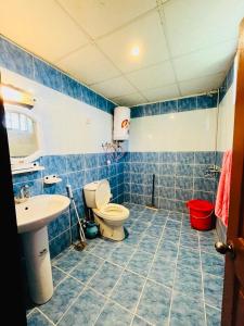 a blue tiled bathroom with a toilet and a sink at Bhurban Lodges in Murree