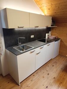 a kitchen with white cabinets and a sink at Brunelle, Obertörgglerhof in Brixen +2 photos