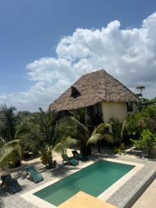 a resort with a swimming pool in front of a building at Happy Villas in Paje