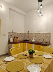 a dining room table with yellow chairs and a kitchen at Kashivas - 2BHK near Assi Ghat in Varanasi +39 photos