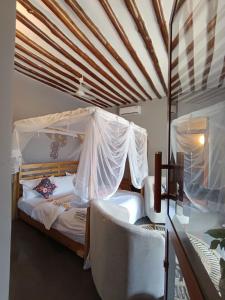 a bedroom with a bed with a canopy and two chairs at Happy Villas in Paje +32 photos