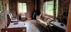 a living room with a couch and chairs and windows at Joy River Backpackers in Moremela