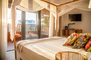 a bedroom with a canopy bed and a balcony at Maison de clara in Ngaparou +47 photos