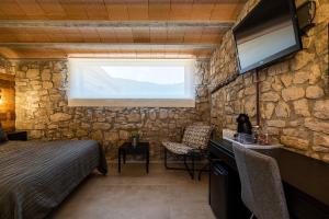 a bedroom with a stone wall with a bed and a television at Les Muntades in Jorba