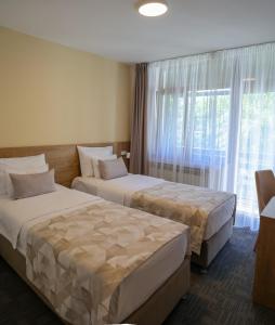 two beds in a hotel room with a window at Hotel Radan Prolom Banja in Prolomska Banja +84 photos