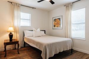 a bedroom with a bed with white sheets and a ceiling fan at Extended Stay SoCo Oasis Outdoor TV, Heavenly Bed, Long Stay Ready in Austin