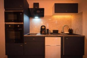 a kitchen with black cabinets and a sink and a microwave at l'Escale Royale in Rambouillet