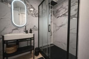 a bathroom with a sink and a shower with a mirror at l'Escale Royale in Rambouillet