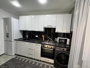 a kitchen with white cabinets and a washer and dryer at Apartament Edinet in Edineţ +2 photos