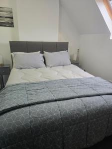 a bed with a gray comforter and two pillows at Tor's Place in Portree