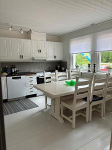 a kitchen with white cabinets and a table and chairs at Chilla villa in Leryd