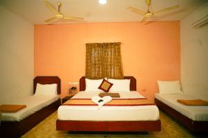 two beds in a room with orange walls at Hotel Raaj Bhaavan - US Consulate - Nungambakkam in Chennai