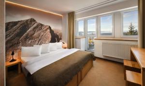 a hotel room with a large bed and windows at Vila Emma in Štrbské Pleso