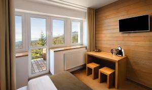 a hotel room with a bed and a tv on a wall at Vila Emma in Štrbské Pleso
