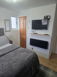 a bedroom with a bed and a flat screen tv on a wall at Tor's Place in Portree