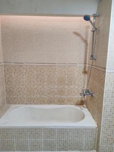 a bath tub in a tiled bathroom with a shower at King bed sea view in Sharjah