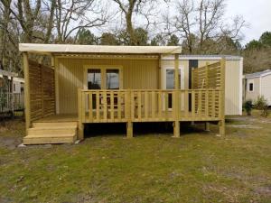 a small yellow house with a large deck at Camping le Laha in Lesperon