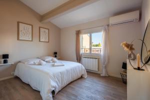 a bedroom with a white bed and a window at Maison Flammarion - Welkeys in Avignon