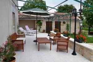 a patio with a table and chairs and an umbrella at Les lilas in Lhommaizé