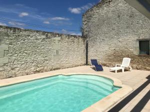 a swimming pool with two chairs and a stone wall at Gîte lamarlière in Savigny-sous-Faye