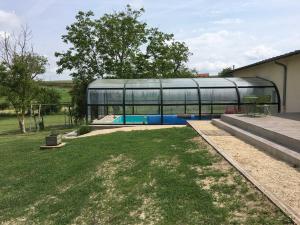 a glass house with a swimming pool in a yard at La prée in Seligny