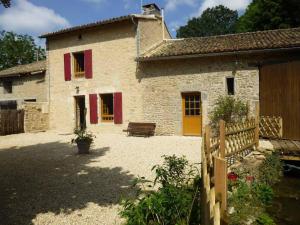 an old stone house with red shutters and a bench at Le moulin de preuillé in Valence en Poitoux