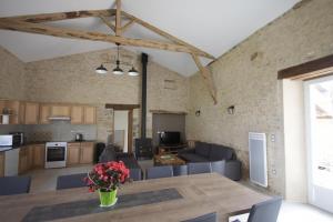 a kitchen and living room with a table and chairs at Les pierres de la dive in Valence en Poitoux