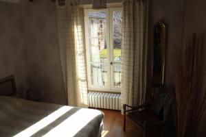 a bedroom with a bed and a window and a chair at Les saules in Persac