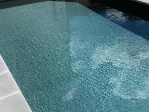 a swimming pool with blue water in it at Les saules in Persac +11 photos