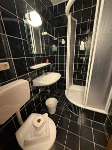 a black tiled bathroom with a toilet and a shower at Motel Haid in Linz