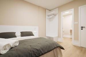 a white bedroom with a large bed in it at Hostal Pico de Noro in Ribeira