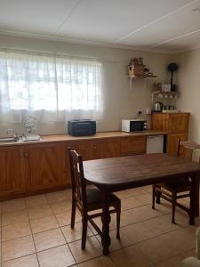 a kitchen with a wooden table with chairs and a sink at Boschberg Accommodation in Somerset East