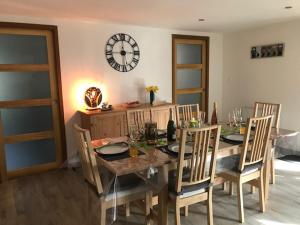 a dining room table with chairs and a clock on the wall at Le chalet des forges in Mairé