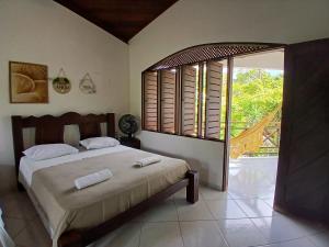 a bedroom with a bed and a large window at Casa charme pipa in Pipa