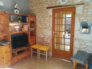 a living room with a television and a table and chairs at La maison de gatienne in Coussay-les-Bois